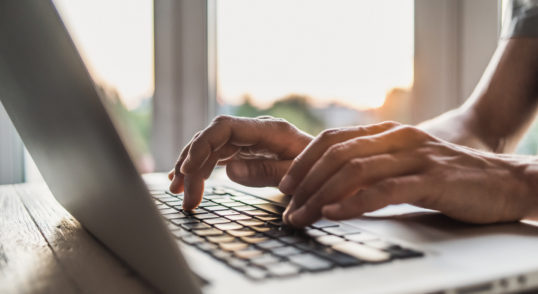man is typing on laptop
